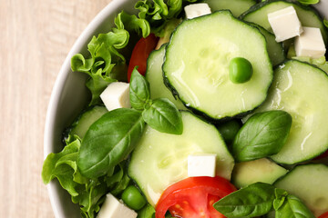 Tasty fresh salad with cucumber in bowl on table, top view