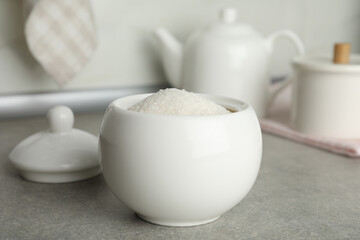Fototapeta na wymiar Ceramic bowl with white sugar on grey table