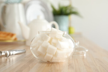Fototapeta na wymiar Glass bowl with white sugar cubes on wooden table