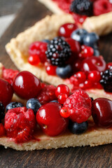 Piece of fruit tart with blackberries, raspberries, blueberries, cherries and red currants.