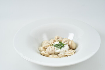 dumplings with sour cream with herbs on a white plate