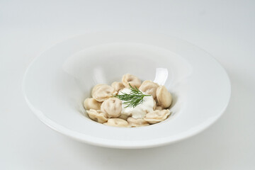 dumplings with sour cream with herbs on a white plate