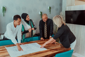  Diversity group working together on architectural project in office interior, young male and female creative graphic designers collaborating during brainstorming using modern technology