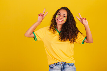 Young black Brazilian woman, soccer fan. peace and love sign with fingers, good vibes