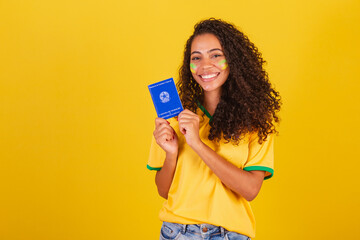 Young black Brazilian woman, soccer fan. holding a work card and social security.