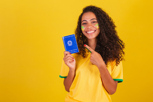 Young black Brazilian woman, soccer fan. holding a work card and social security.