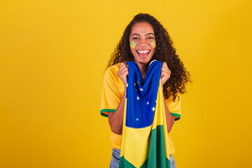 Young black Brazilian woman, soccer fan. with brazil flag. vibrating smiling