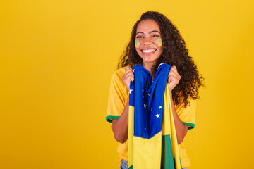 Young black Brazilian woman, soccer fan. with brazil flag. vibrating smiling