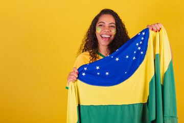 Young black Brazilian woman, soccer fan. with brazil flag. cheering and celebrating.