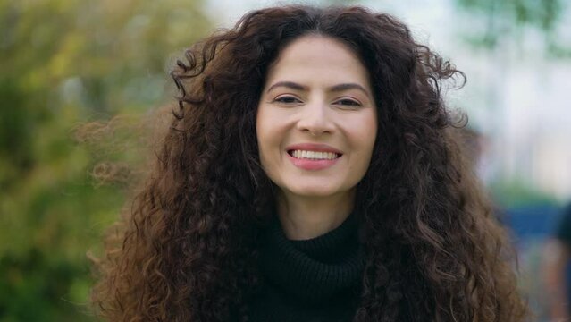 Portrait of a happy young woman standing outside. Female person closeup face with long hair looking at camera smiling