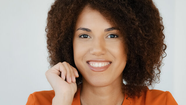 Pensive confused African American woman 20s curly haired smart girl pondering thinking creative plan thinks deep in thoughts comes up with ideas raised finger up smiling has insight close up portrait