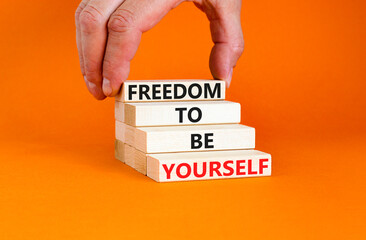 Freedom to be yourself symbol. Concept words Freedom to be yourself on wooden blocks on a beautiful orange background. Businessman hand. Business, psychological freedom to be yourself concept.