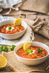 Bowls with Solyanka, a spicy and sour soup of Russian origin, on wooden background. Soljanka is well known in East European countries and East Germany. Vertical.