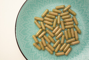 green plate with handful of kratom pills laying randomly, selective focus