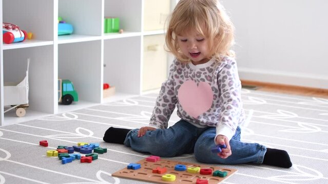 Cute caucasian blonde little toddler girl playing with toys in her room