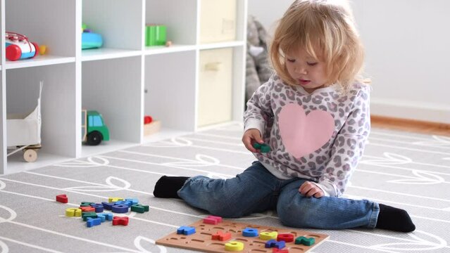 Cute caucasian blonde little toddler girl playing with toys in her room