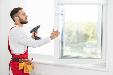 handsome young man installing bay window in a new house construction site.