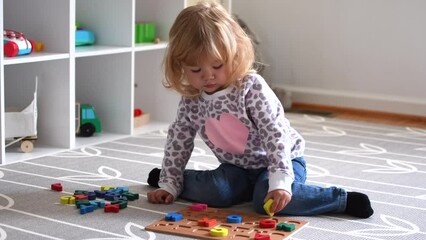 Cute caucasian blonde little toddler girl playing with toys in her room