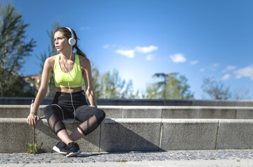 healthy woman resting and listening music with mobile phone while doing yoga and workout