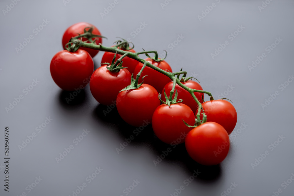 Wall mural Cherry tomatoes and rosemary on a black background. Fresh tomato branch. Vegetarian food. - Wall murals