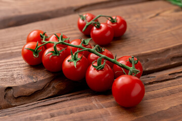 Cherry tomatoes on a wooden background. Fresh tomato branch. Vegetarian food.