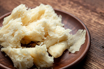 Hard cheese sliced chips on a clay plate on a wooden background.