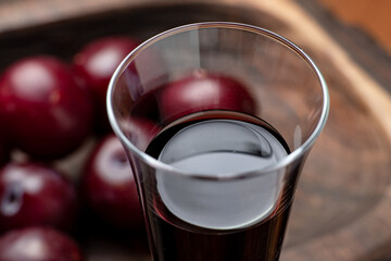 Plum red wine on a dark wooden background. Glass with red wine close up.