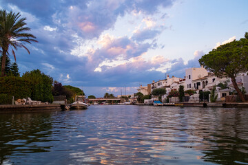 Obraz premium Empuriabrava spanish town in view of main water channel with boats at dusk. Landscape of the catalan town in the Costa Brava region known for its canals and marina
