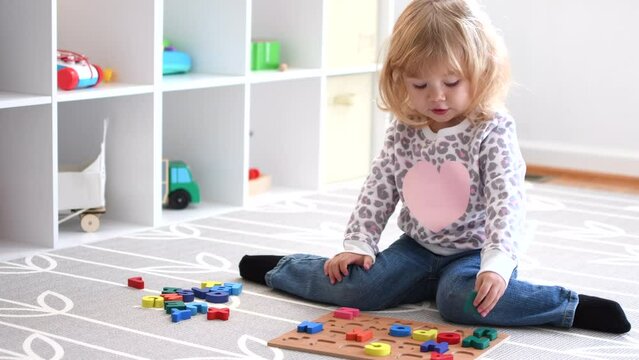 Cute caucasian blonde little toddler girl playing with toys in her room