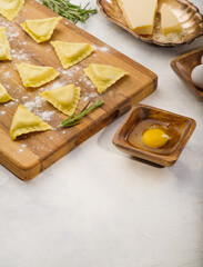 Raw homemade ravioli on a wooden cutting board. Ingredients on a white background. Cooking Italian cuisine. Home recipes. Book of recipes. There is free space to insert.