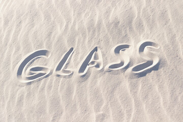 word glass written on white sand, material for glass production
