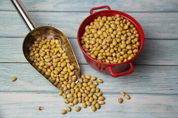 Yellow Ball Beans (Phaseolus vulgaris) in a stainless steel measuring spoon and red pot on a wooden...