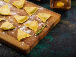 Home kitchen. Raw Italian ravioli on a wooden cutting board on a marble background. Dishes of Italian cuisine. Restaurant and home recipes. Organic food. Healthy lifestyle.