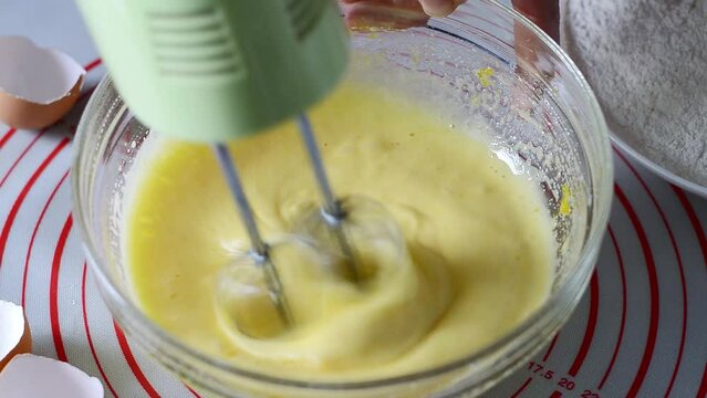 Mixer in motion whipping egg in a glass bowl to make omelet or dought, close-up