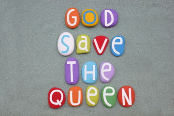 God save the Queen, creative slogan composed with multi colored stone letters over green sand