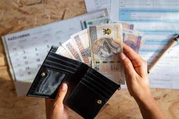 the girl holds in her hands a wallet and zloty paper banknotes for payment - obrazy, fototapety, plakaty