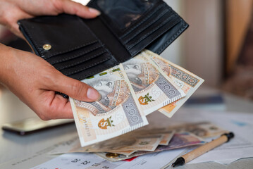 the girl holds in her hands a wallet and zloty paper banknotes for payment