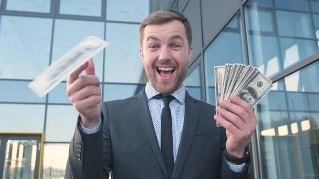 Insanely happy rich young man holding a stack of dollars and throwing them. 