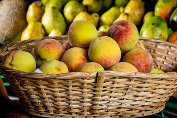 basket full of fruits. group of peaches in a basket. fruits for sale in the market. market place in Latin America. fruits for sale in the traditional way. 
