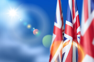 National flags of United Kingdom on a flagpole on blue sky background. Lowered UK flags. Background...