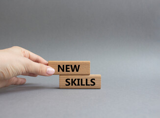 New skills symbol. Wooden blocks with words New skills. Beautiful grey background. Businessman hand. Business and New skills concept. Copy space.