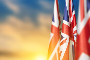 Fototapeta National flags of United Kingdom on a flagpole on sunset sky background. Lowered UK flags. Background with place for your text. obraz