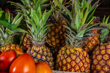 pineapples in the market. pineapple cluster in latin america. pineapples next to tree tomatoes. sweet fruits. tropical fruits. 