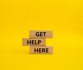 Get help here symbol. Wooden blocks with words Get help here. Beautiful yellow background. Business and Get help here concept. Copy space.