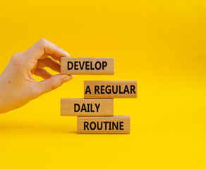 Develop a regular daily routine symbol. Concept words Develop a regular daily routine on wooden blocks. Beautiful yellow background. Businessman hand. Business and concept. Copy space.