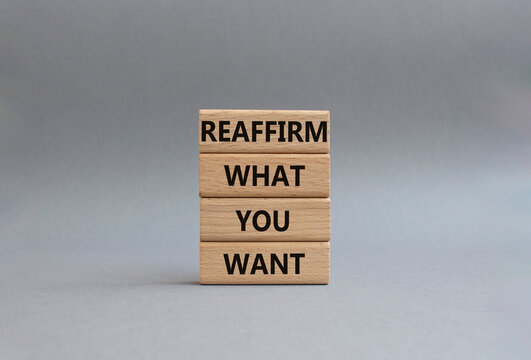 Goals symbol. Wooden blocks with words Reaffirm what you want. Beautiful grey background. Business and Reaffirm what you want concept. Copy space.