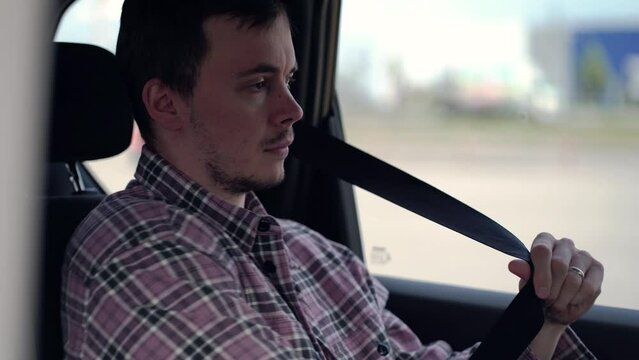 Tired guy getting into a taxi after work and fastening his seat belt