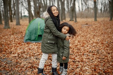 Naklejka na ściany i meble Two little black sisters in tent camping in the autumn forest