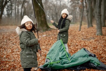 Two little black sisters in tent camping in the autumn forest