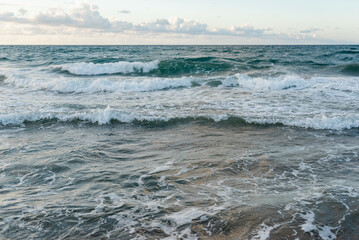 Background image of turquoise sea waves on a sunny day.